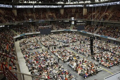 Miles de personas en un estadio techado durante una convención de los testigos de Jehová.