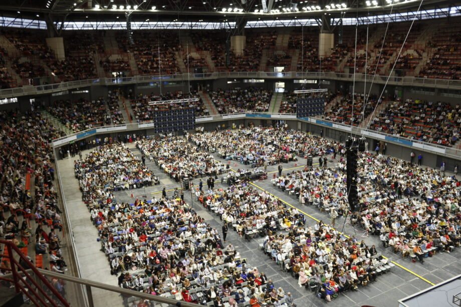 Miles de personas en un estadio techado durante una convención de los testigos de Jehová.